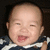 Pixelated close-up of a smiling baby with closed eyes, wearing dark blue and white striped clothing against a black background.