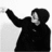 Pixelated grayscale image of a figure in a hooded coat with one arm raised, set against a light background.