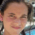 A person with dark hair tied back smiles in a of four showing subtle facial expression changes