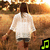 A person in a white shirt and dark shorts walks through a sunlit field with trees, while the musical note symbol changes color.