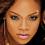 Pixelated close-up of a person's face with light brown skin tone, dark eyes, and pink lips against a blurred background.