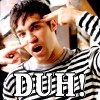 A person in a black-and-white striped shirt with a white undershirt, making a gesture with both hands near their head, with large text reading "DUH!" at the bottom.