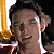 A pixelated close-up of a person with dark hair, closed eyes, and a slight smile, holding a golden trophy-like object against a dark background.