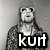 Pixelated grayscale image of a person with long hair wearing a dark jacket over a light shirt, overlaid with bold white text reading 'kurt' on a black background.