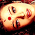 Pixelated cartoon face with large eyes, red cheek spots, and a wide open mouth showing teeth, set against a dark background.