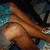 A pixelated image of a person's legs and feet in brown shoes on a patterned floor, with a visible leg and foot in the foreground.