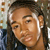 Pixelated static image of a person's face with dark hair and light skin, wearing a dark shirt against a blurred background.