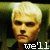 Pixelated image of a person with short light-colored hair and dark eyes, wearing a dark shirt against a green background with text at the bottom.
