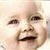 Pixelated close-up of a smiling baby's face with visible eyes, nose, mouth, and cheeks against a light background.