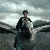 Animated sequence showing a figure in dark clothing standing on rocky terrain with another figure in the foreground wearing light-colored shirt and bow tie, both against overcast sky.