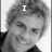 A black-and-white pixelated image of a person with curly hair, smiling, with text overlays changing across frames.