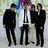 Four figures in formal attire stand against a pixelated background with green, blue, and purple hues.