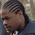 Static 50x50 pixel buddy icon showing a close-up of a person's face with braided hair, wearing a dark jacket and light-colored shirt with a green accent on the collar.