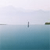 A static image of a calm body of water with a vertical gray post in the center, a small dark green structure on the right, and a faint horizontal line across the middle.