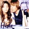 Two people in a close pose with long hair and dark blue vests over white shirts, with 'Hide' text and a heart symbol changing position across frames.