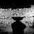 Black and white pixelated image showing a dark central shape against a textured background with scattered light and dark pixels.