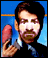 A person in a dark suit and light blue shirt holds a large pink sausage-like object against a blue background with an orange stripe.