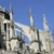 Pixelated static image of a light-colored building with multiple spires against a solid blue background, showing architectural details and partial shadows.