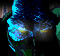 Animated sequence of a blue and green pixelated figure with glowing yellow eyes, showing subtle shifts in eye brightness and head position across frames.