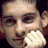 Pixelated static image of a person's face with visible facial features and partial body, rendered in low resolution.