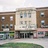 Pixelated static image of three adjacent multi-story buildings with varied facades and ground-floor storefronts under a light sky.