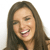 Pixelated close-up of a person with long brown hair smiling broadly, showing teeth, against a plain white background.