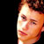 Static 50x50 pixel icon showing a close-up of a person's face with orange and brown tones against black background, cropped to right side of head.