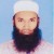 Pixelated image of a person with a light-colored head covering, dark beard, and dark clothing against a light blue background.