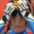 Pixelated static image of a person wearing a white and black patterned hat with yellow accents, blue clothing, and red details against an orange background.