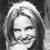 Black-and-white pixelated static image of a person's face with shoulder-length hair, visible in grayscale tones on a dark background.