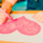 A pixelated image shows a person wearing a pink dress with a white background and colorful upper section.