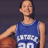Pixelated static image of a person in a blue basketball jersey holding a basketball against a dark background.