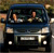 Static pixelated image of a dark blue vehicle with two visible figures inside, one in the driver's seat and one in the passenger seat, both with raised arms.