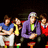 Group of five people seated in a , wearing blue, yellow, purple, red, and white clothing with visible green accents