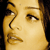 Pixelated close-up of a person's face showing eyes, nose, and mouth with warm yellow-brown tones against dark background.