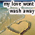 Pixelated image with text 'my love wont wash away' over a beach scene featuring sand, water, and a heart-shaped object.