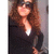 A pixelated static image shows a person with long brown hair wearing dark sunglasses and a black top, holding their hand near the face.
