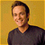 Pixelated portrait of a person with short dark hair wearing a dark V-neck shirt against a yellow background.
