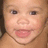 Pixelated close-up of a smiling child's face with visible eyes, nose, mouth, and light skin tone.
