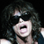 Pixelated close-up of a person with voluminous dark curly hair, mouth open in a shout or yell, against a solid black background.