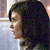 Pixelated profile view of a person with dark hair against a light background, showing partial facial features and clothing details.