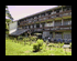 Two side-by-side pixelated images show a building with multiple windows and greenery on the left, and a path with trees and a distant structure on the right.