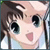 Pixelated anime-style icon of a character with brown hair and large black eyes, smiling with pink lips against a light background.