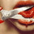 A close-up of a person's mouth with red lips and white teeth, partially covered by a gray fabric strip.