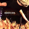 A static image shows a person in a black shirt with a skull design, holding a microphone, with flames at the bottom and the text 'HARDXCORE.' in pixelated white letters.