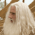 Pixelated static image of a figure with long white hair and a light-colored robe, set against a brown and white background.