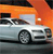 A silver sedan with black trim is positioned on a road under an orange sky, viewed from a low angle with visible wheels and side windows.