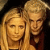 Two pixelated figures with light brown hair stand close together against a dark background, their faces partially visible in low-resolution detail.