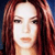 Pixelated close-up of a person with long reddish-brown hair against a dark blue background, showing facial features and upper shoulders.
