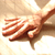 A hand performs a sequence of gestures on a light wooden surface, transitioning from spread fingers to a fist and back to a relaxed position.